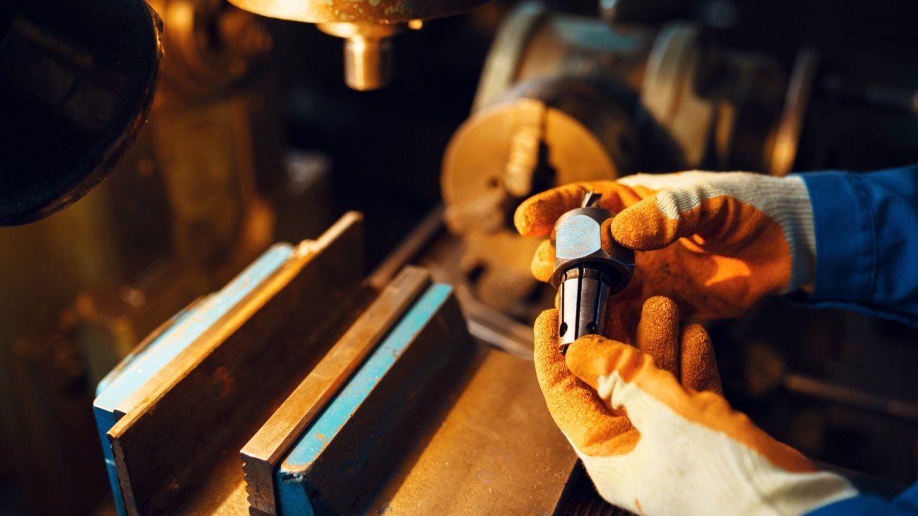 worker-hands-holds-detail-lathe-on-background-GYT5E6L